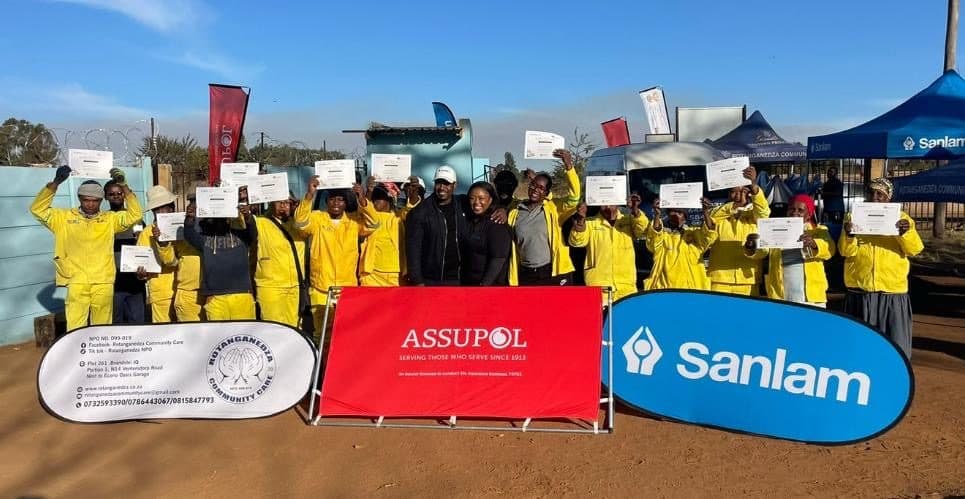 Group of trainees in yellow overalls holding up their certificates